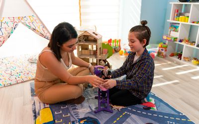 Little boy in child occupational therapy session doing sensory playful exercises with his therapist