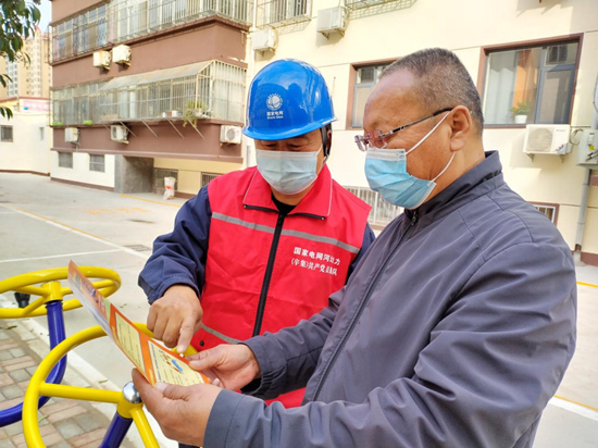 國網辛集市供電公司共產黨員服務隊隊員向辛集市皮毛廠西社區居民講解冬季用電注意事項。路沖攝